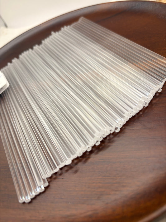 A close-up of a fan of clear plastic or acrylic rods or strips resting on a dark brown wooden surface.