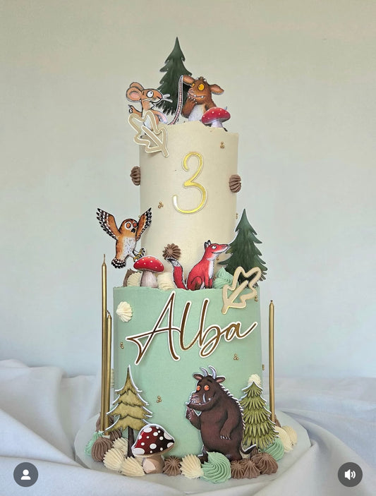 Two-tiered birthday cake with animated characters and 'Alba' on a white background