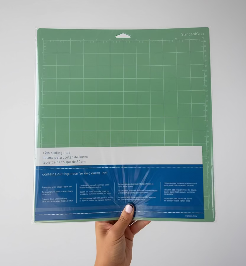 A person's hand holds a packaged green StandardGrip quilting mat with a blue and white paper label, positioned in front of a white paneled door.