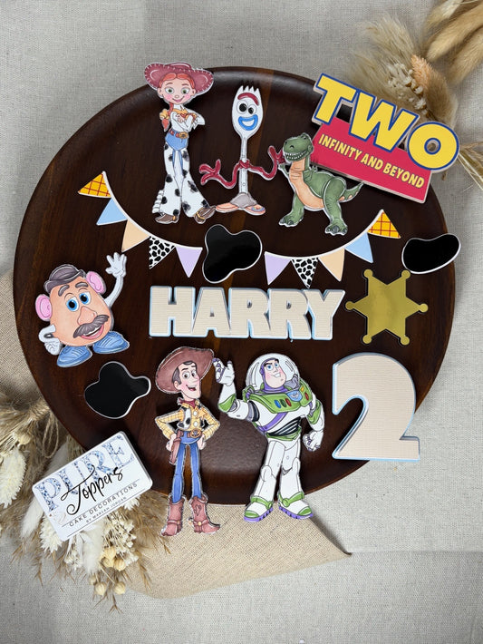 Personalised Toy Story–inspired cake topper set with layered characters, custom name and age, “To Infinity and Beyond” sign, bunting, badge, and cow print charms on a birthday cake.