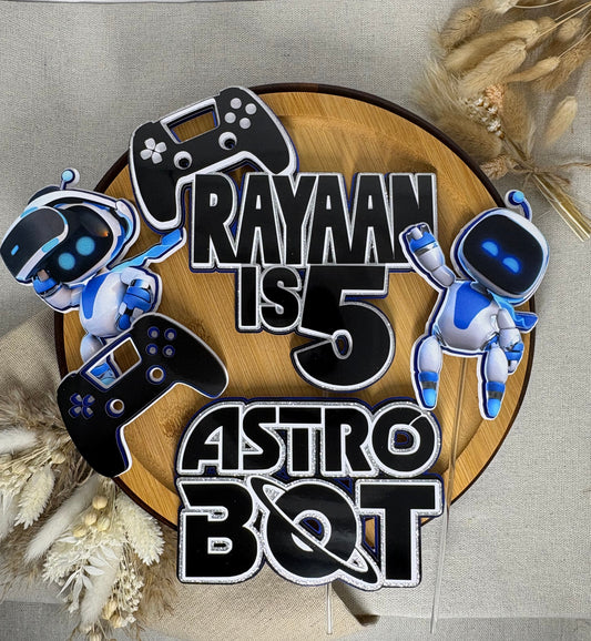 Layered gaming birthday cake topper featuring Astro Bot characters and controllers