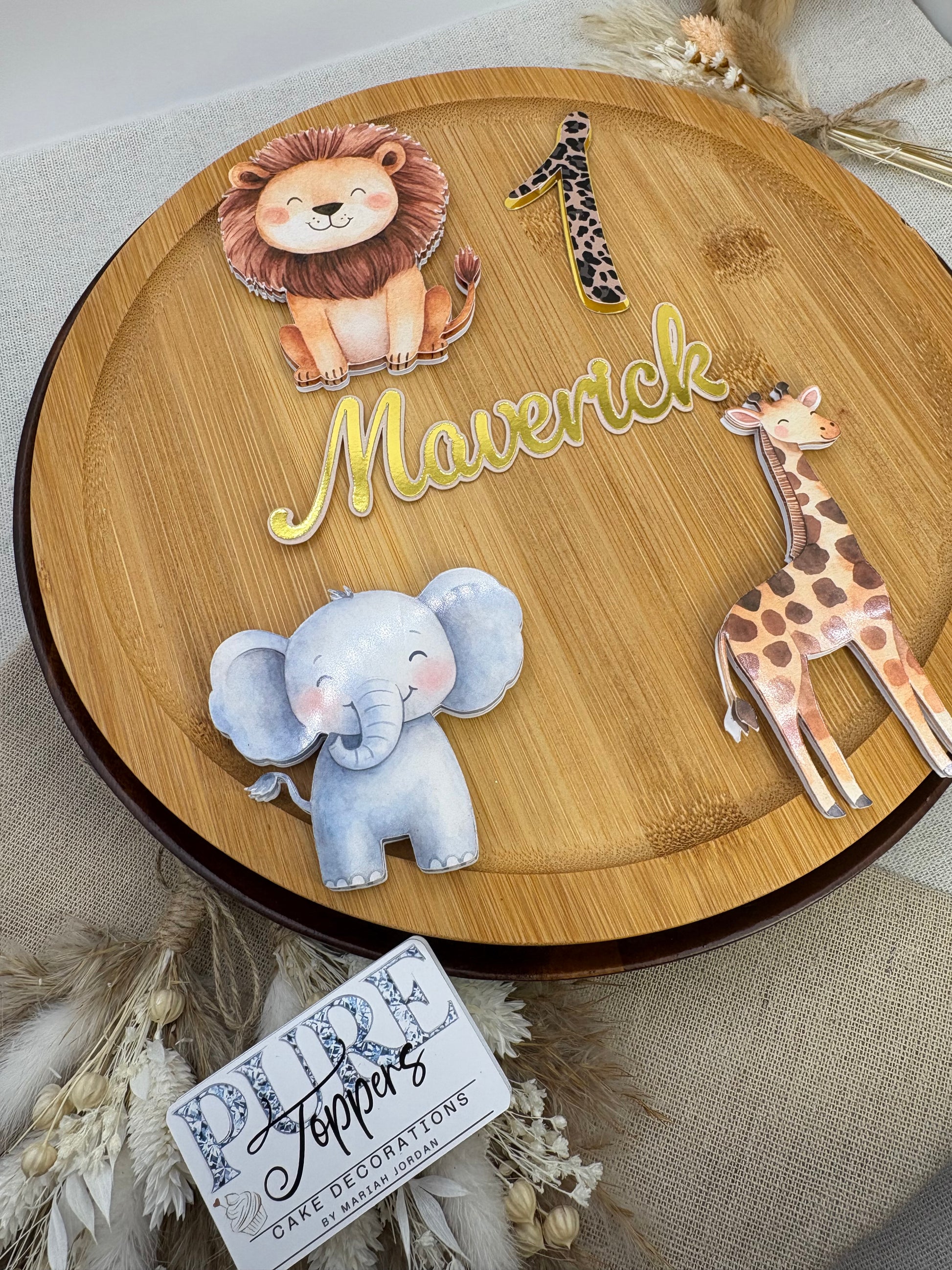 Wooden decorative plate with animal figurines and a name on a neutral background