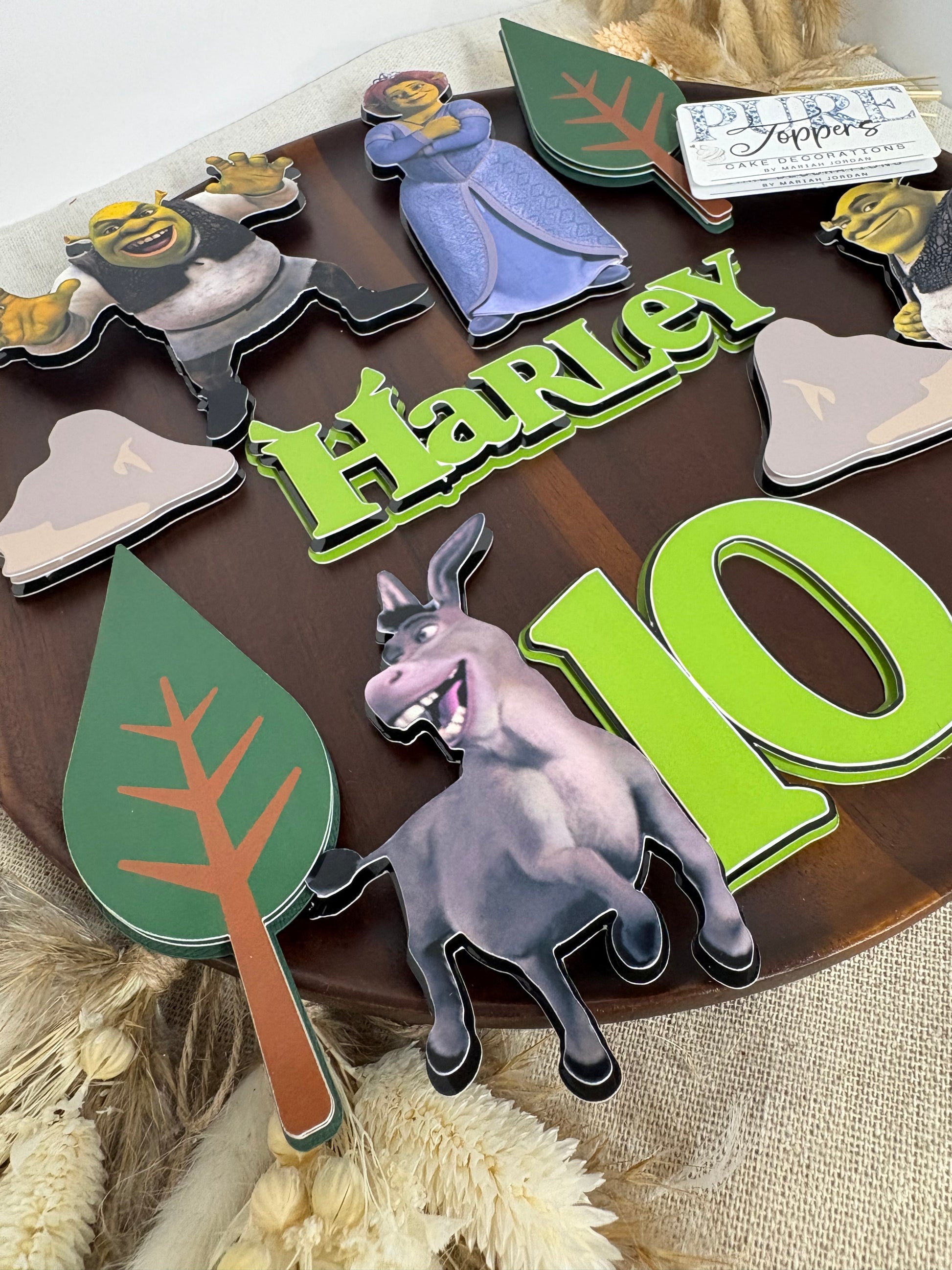 Personalised Shrek birthday cake topper with layered woodland trees, rocks and custom name decoration.