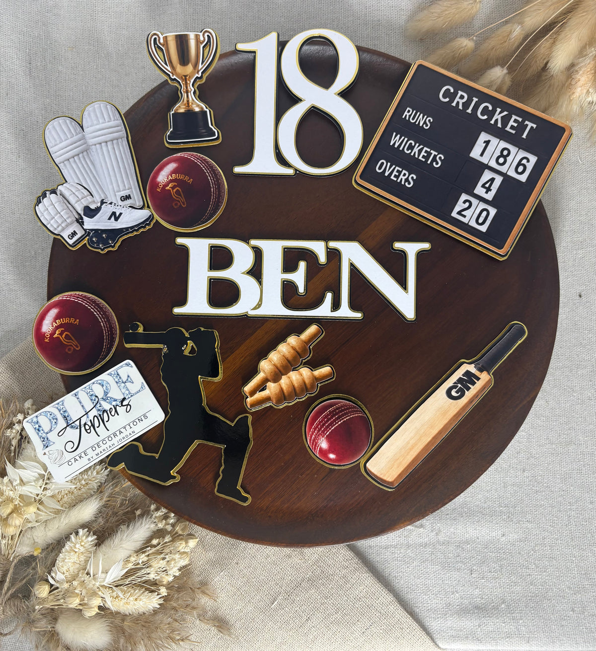 Close-up of personalised cricket cake topper lettering with triple-layered white, black and gold foil details