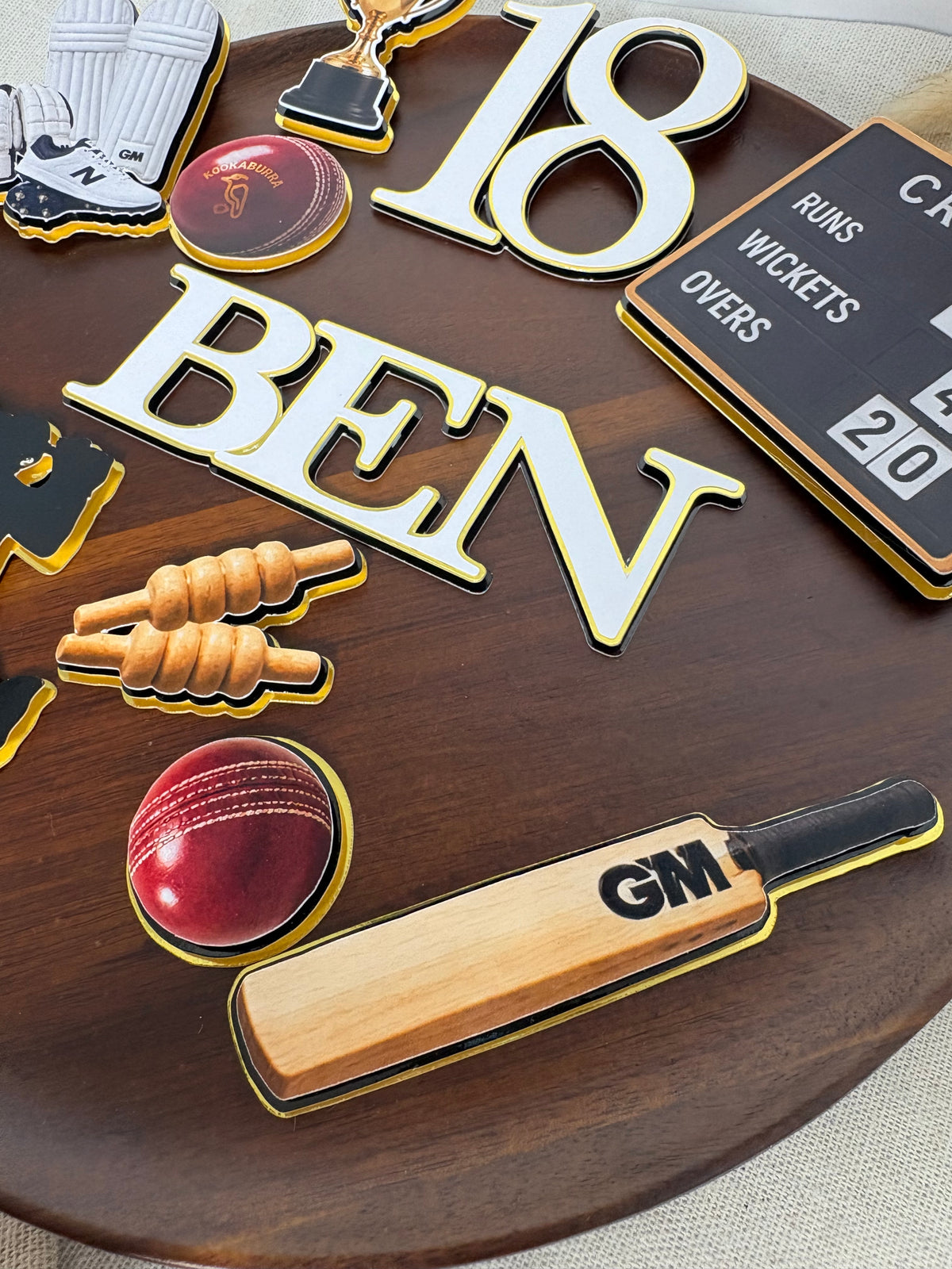 Personalised triple-layered cricket birthday age topper attached to a cake topper stick