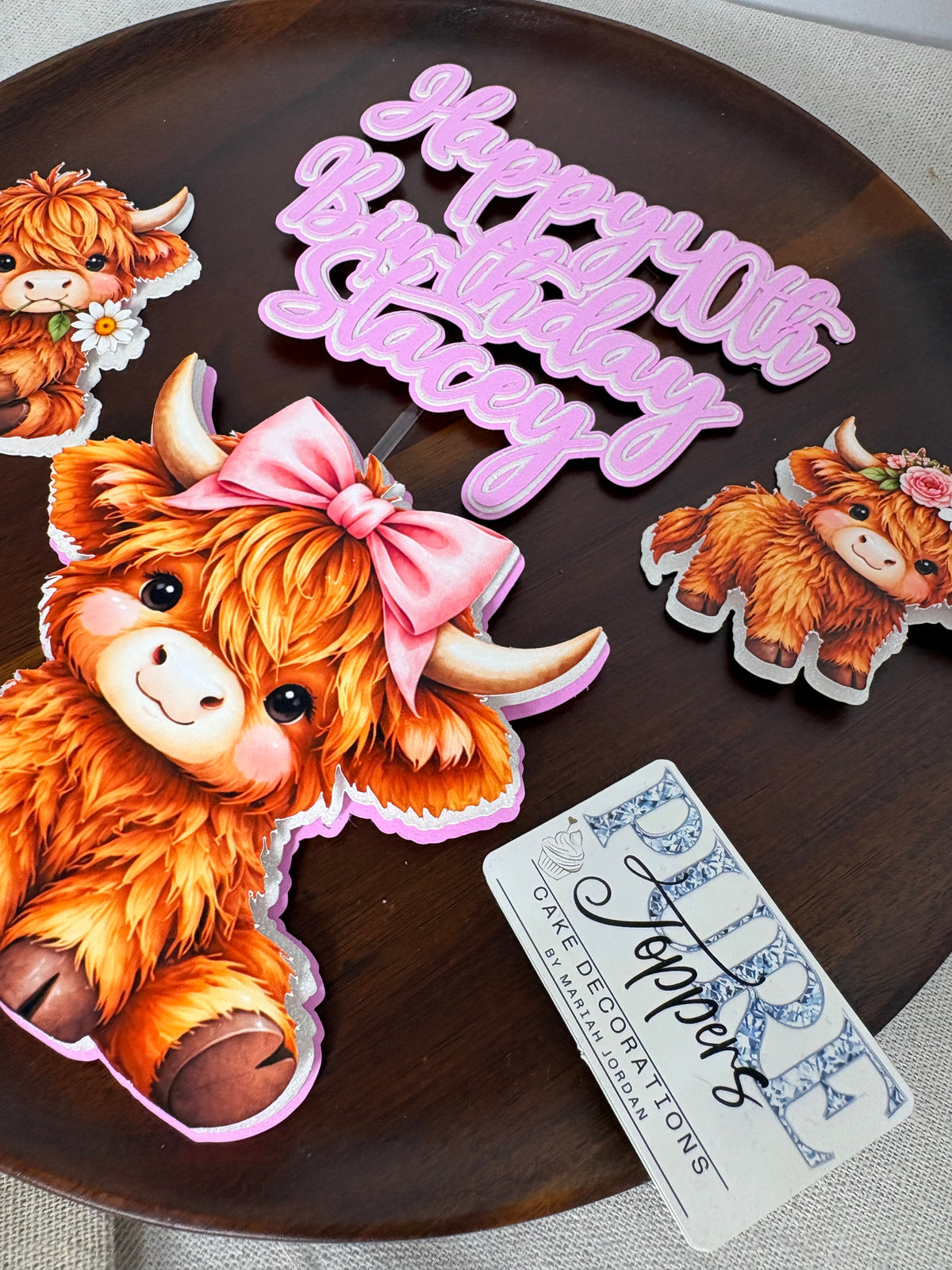 Two cute Highland cow birthday cake toppers attached to sticks
