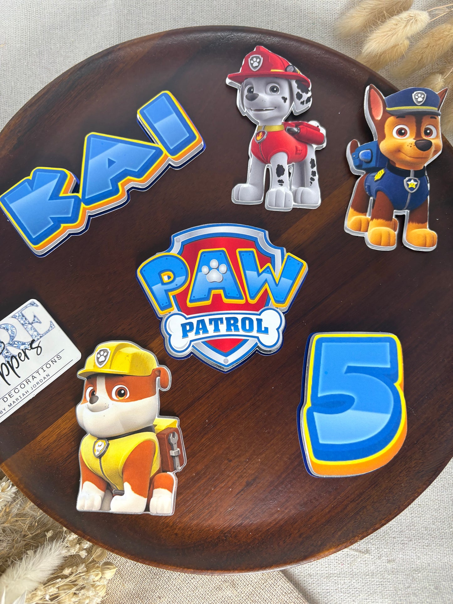Layered Paw Patrol birthday cake decorations with three pup characters and logo