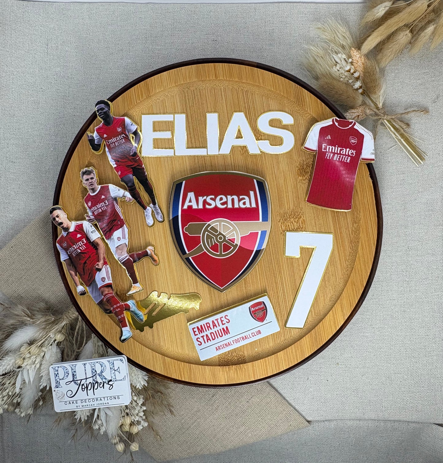 Wooden plaque with Arsenal FC logo, player images, and jersey on a textured surface.