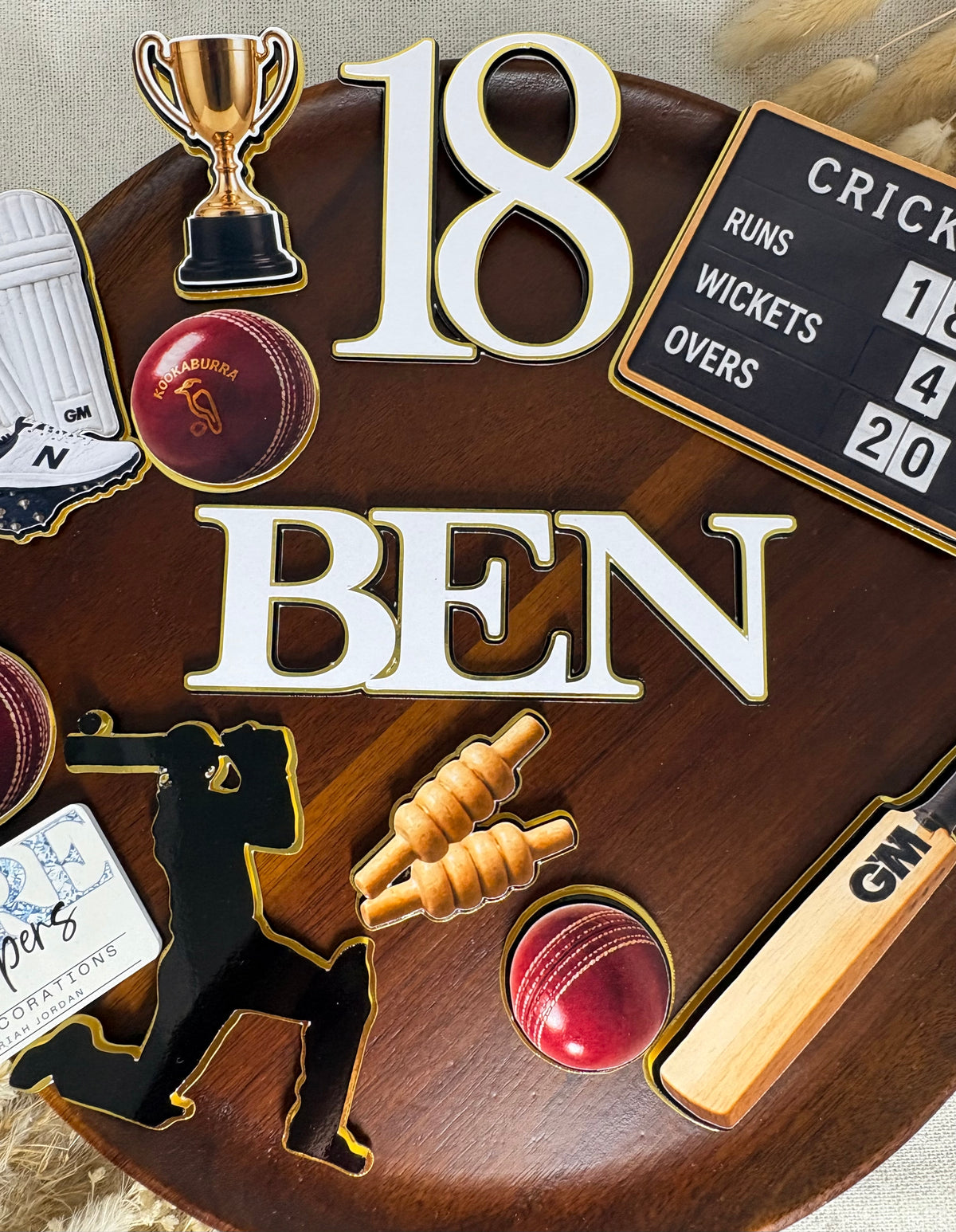 Individual cricket birthday cake decorations including cricket bats, balls, shin pads and player silhouette